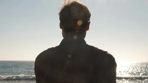 Man looking at the surf in the sun glare Stock Footage 96609121