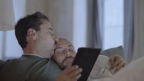 Man looking at tablet screen, lying in bed with lover in morning Video stock 229635543