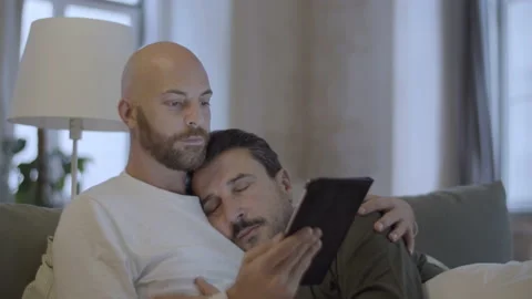 Man looking at tablet screen while lying in bed with lover Stock Footage 229633973