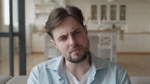 Man Looking Thoughtfully At Camera, Sitting Indoors With Curious Expression Stock Footage 306695452