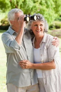 A man is looking through a binoculars and hugs his smiling wife 写真素材