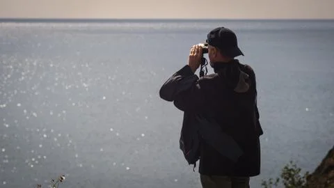 Man looking through binoculars on the Bay Stock Photos