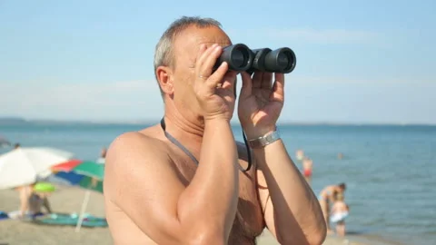 Man is looking through binoculars on beach Video stock 96462619