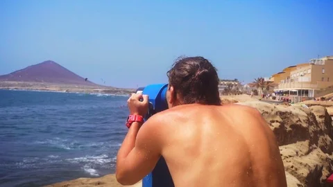 Man looking through binoculars on the coast of the blue sea Stock Footage 71524483