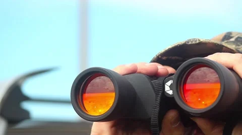 Man looking through binoculars with red glass 스톡 동영상 64682329