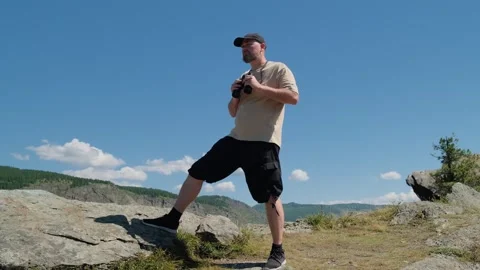 A man looking through binoculars standing on top of mountain. Stock Footage 303577178