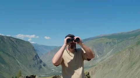 A man looking through binoculars standing on top of mountain. Stock Footage 304959524