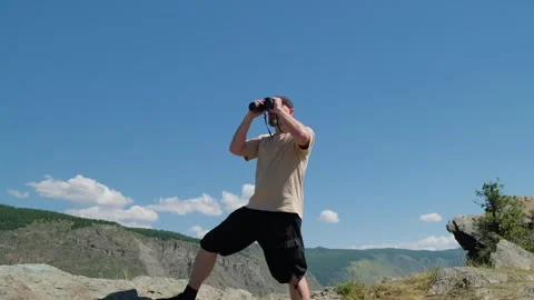 A man looking through binoculars standing on top of mountain. Stock Footage 306030339