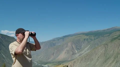 A man looking through binoculars standing on top of mountain. Stock Footage 309894805