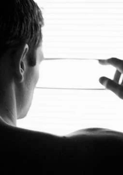 Man looking through blinds, rear view, head and shoulders, partial view, black Stock Photos