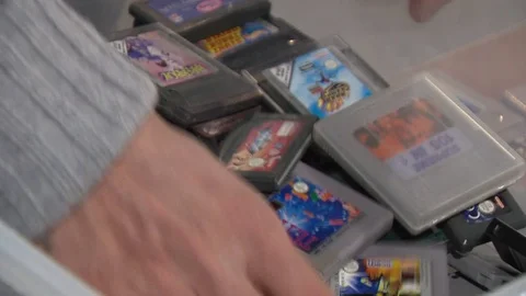 Man looking through a case of old game cartridges Stock Footage 86596049