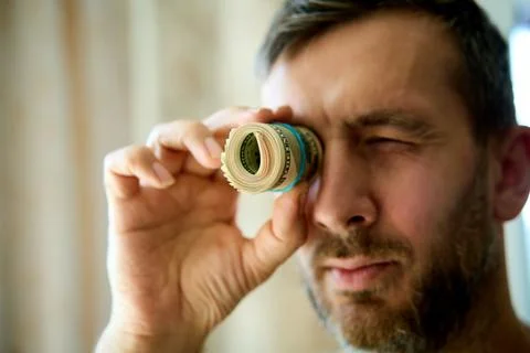 Man looking through dollar bill roll Stock Photos