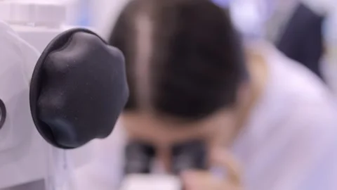 Man is looking through a microscope Stock Footage 299881147