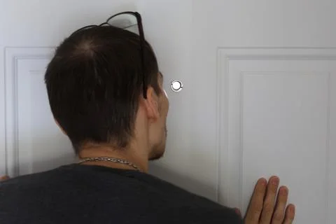 Man looking through peephole from inside checking visitor concept 写真素材