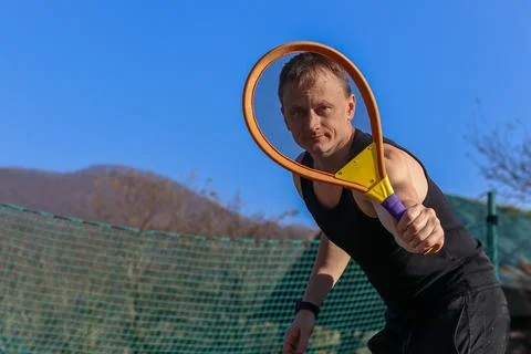 Man looking through racket strings outdoors 스톡 사진