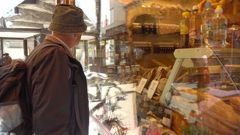 Man looking through store window of bakery Stock Footage 93180388
