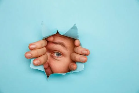 Man looking through torn blue background Stock Photos