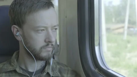 A man looking through the train window and listening to music Stock Footage 136179841