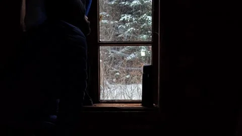 Man Looking Through Window of Dark Rural House at Winter Forest Stock Footage 334239095