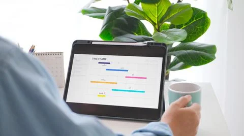 Man looking at time frame planner on digital tablet screen for mobile phone a Stock Photos