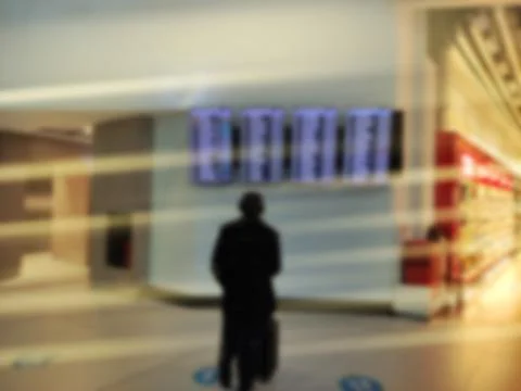 A man is looking at the timetable. Blurry hall. Stock Photos