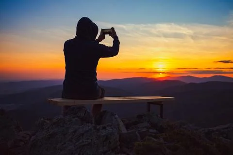 Man looking toward burning sunset sky and panoramic view of mountain hills Stock Photos