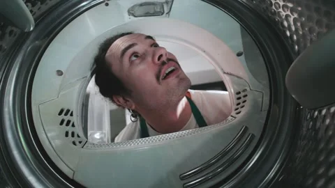 Man looking into a washing machine with a surprised expression in a domestic Stock Footage 305281600