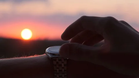 Man looking at wristwatch on sunset background Stock Footage 111970775