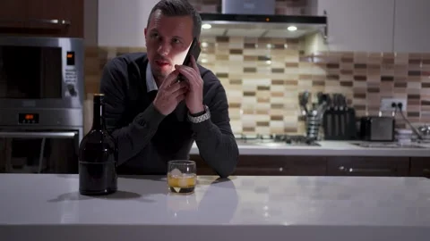 Man Looking at Wristwatch While Talking on Smartphone in Kitchen. A man che.. Video stock 332416042