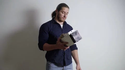 A man looks at an asic for mining, bitcoin, does not understand what to do with Video stock 155054971