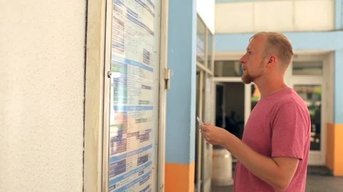 Man looks at the bus schedule Stock Footage 92125630