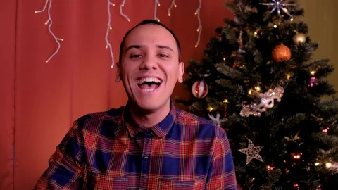 A man looks at the camera and laughs at Christmas. Christmas tree in the Stock Footage 125140083