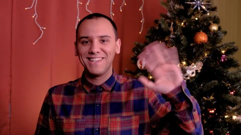 A man looks at the camera and waves a greeting for Christmas. Stock Footage 125140653