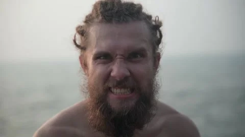 The man looks into the camera with an expression of anger, actively breathing. Video stock 234020119