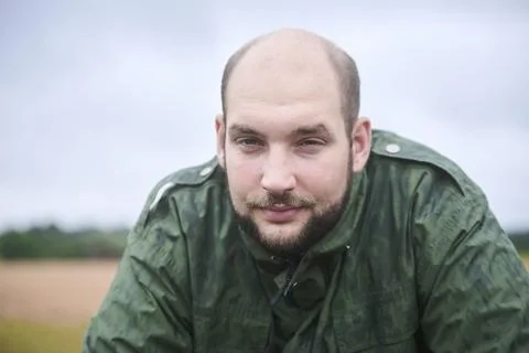 Man looks at camera with friendly expression. He is outdoors, his jacket is w Stock Photos