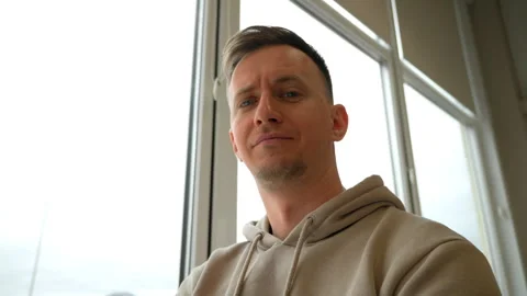 Man looks at the camera with a suspicious look and sits in a large room with Stock Footage 284477757