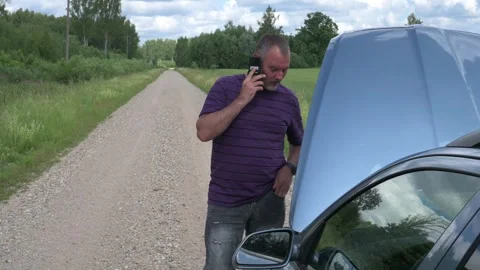The man looks at the car engine on the road, calls, and becomes happy 動画素材 245167932