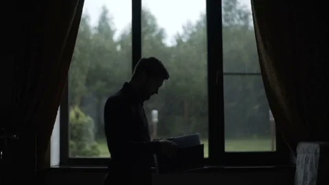 Man Looks at Documents Near Window Stock Footage 78013599
