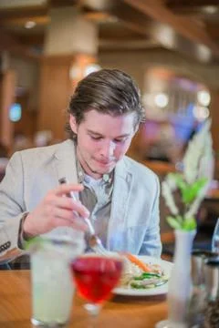 Man Looks Down at Plate while Eating Dinner on Date Stock Photos