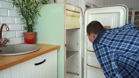 A man looks into an empty refrigerator and then closes it Stock Footage 161657600