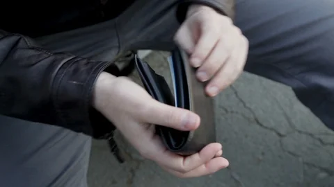 A man looks at an empty wallet and finds a few cents. Stock Footage 102282809