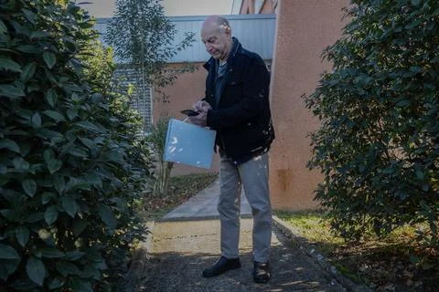 Man looks at his device while standing on the path by shrubs Stock Photos