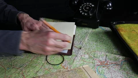 A man looks at a map and writes a route in a notebook Stock Footage 102229914