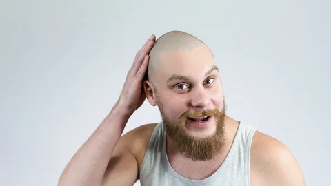 A man looks in the mirror at the reflection of the bald head and rejoice. Stock Footage 122512313