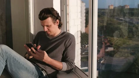 Man looks at mobile phone, flipping the tape in social networks sitting on the Video stock 102449045