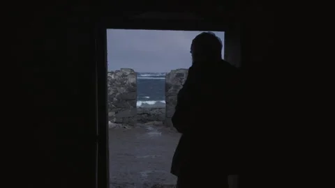 Man looks out at ocean waves during rainy evening in a coastal town Stock Footage 325801450