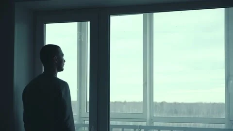 A Man Looks Out Of The Window Of His Apartment. Man Looking Out The Window And Stock Footage 170041699
