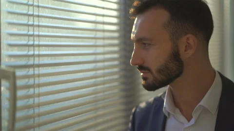 The man looks out the window through blinds Stock Footage 100744222