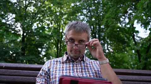 Man looks over glasses checking social networks on tablet Stock Footage