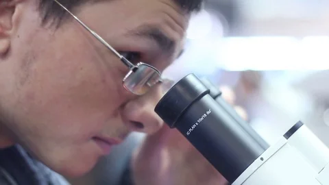 Man looks professional scientific microscope Stock Footage 73385825